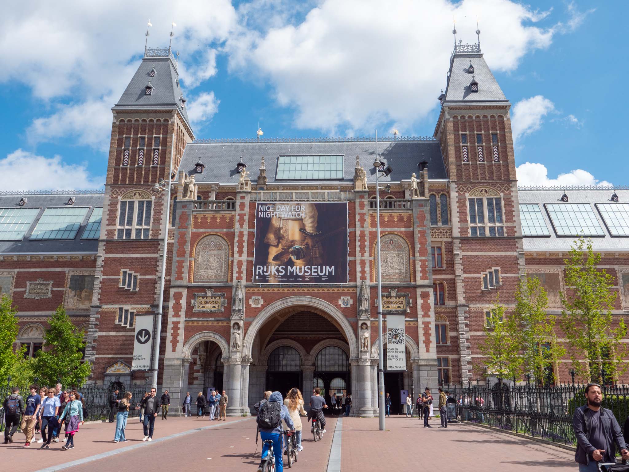 a brick building with people walking around with Rijksmuseum in the background