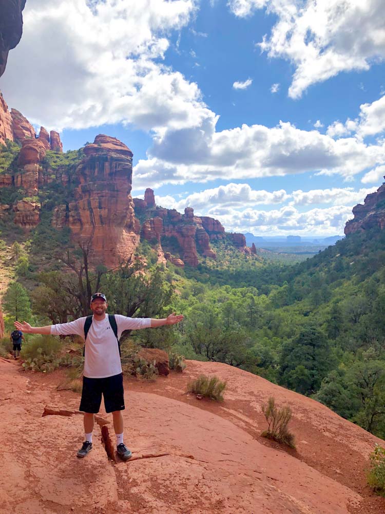 a man standing on a rock with his arms out in the air