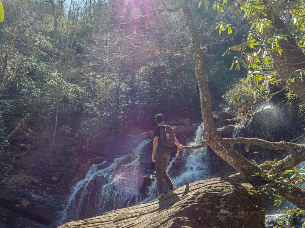 a man standing on a rock near a waterfall