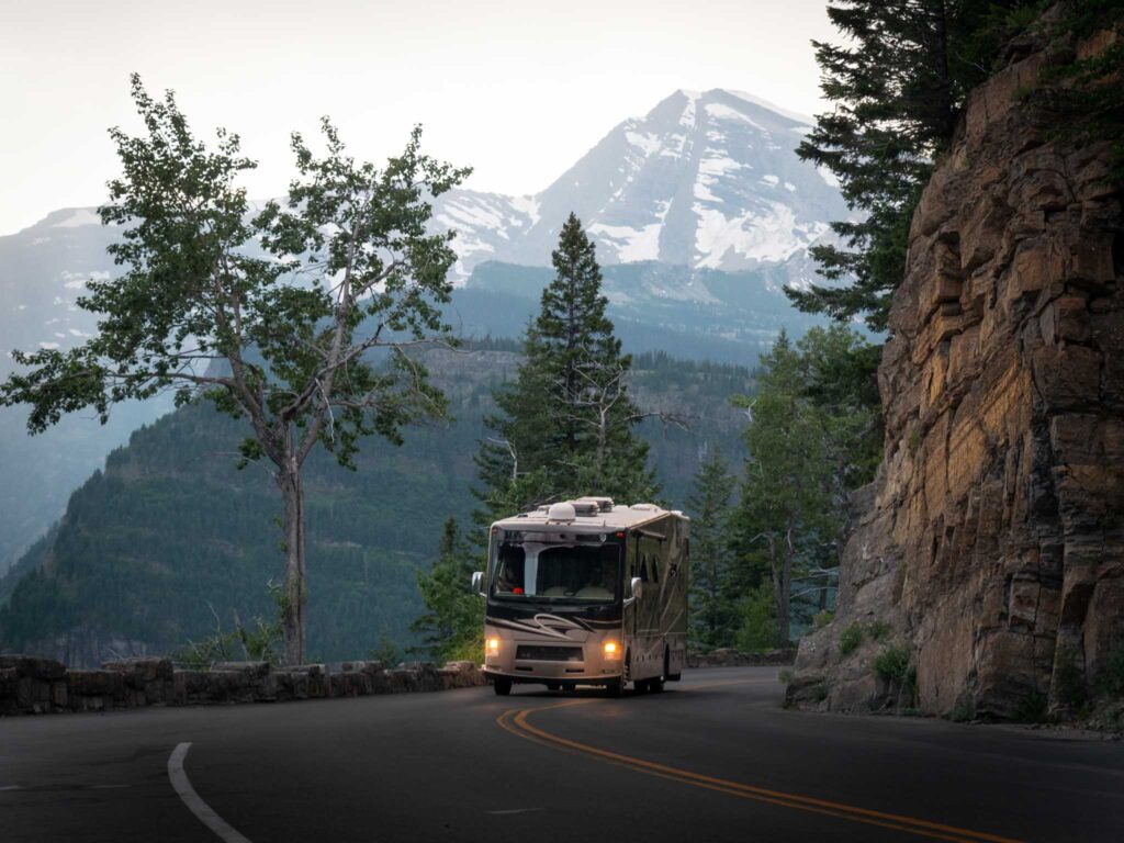 a rv on a road with mountains in the background