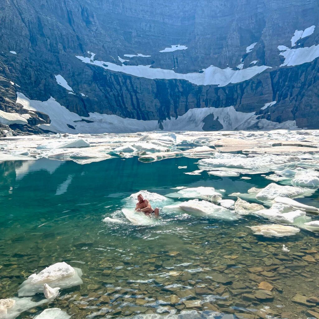 a person swimming in a body of water with icebergs in the background