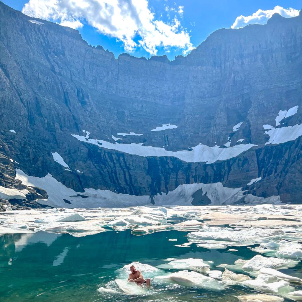 a person swimming in a body of water with icebergs in the background