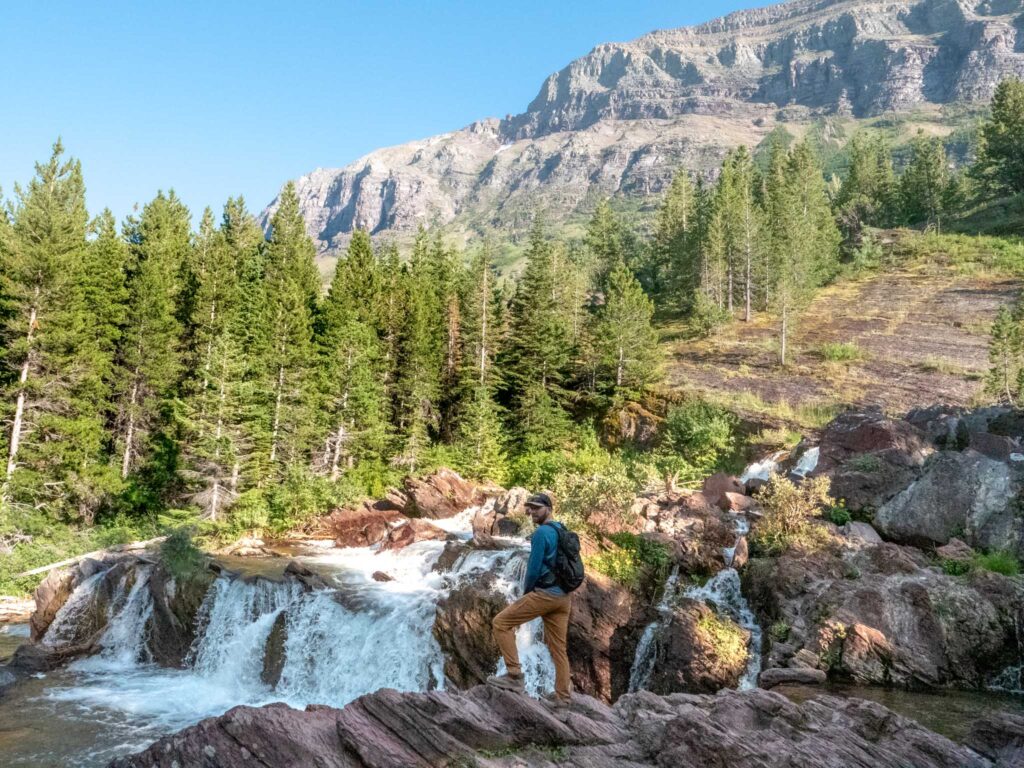 a man standing on rocks near a waterfall