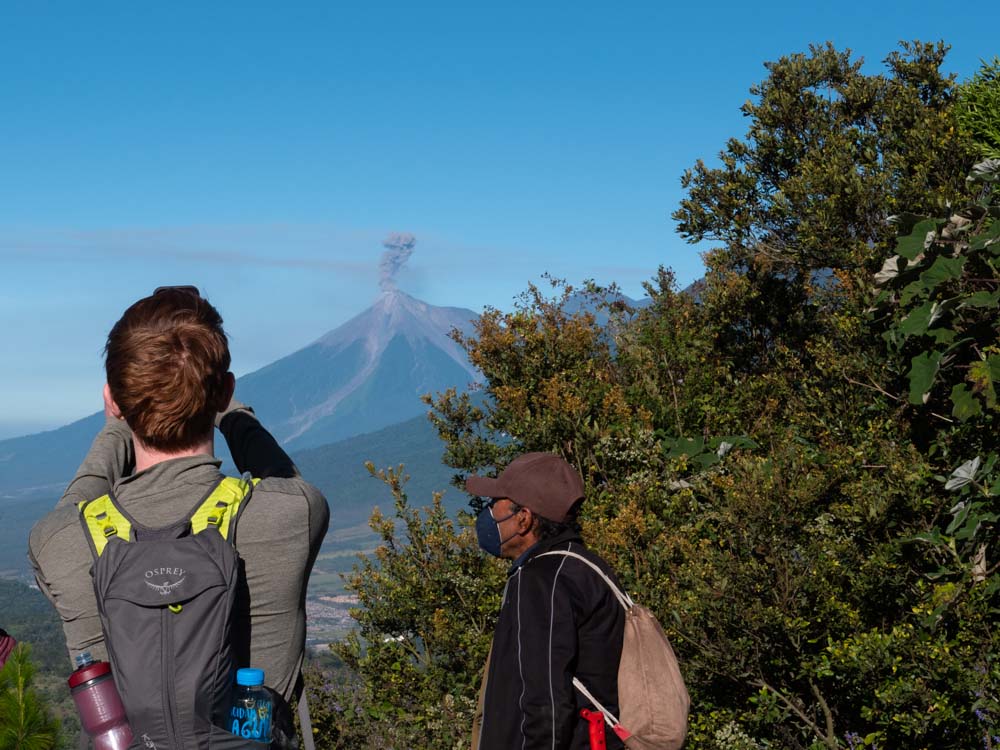 Man taking photo of volcano eruption while hiking to Pacaya Volcano