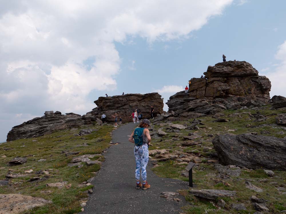 a woman walking on a path with rocks on the side