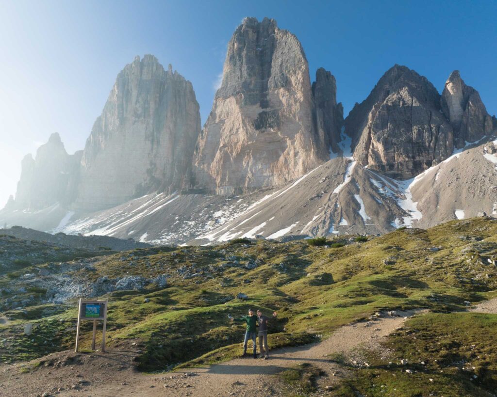 two people standing in a grassy area with mountains in the background