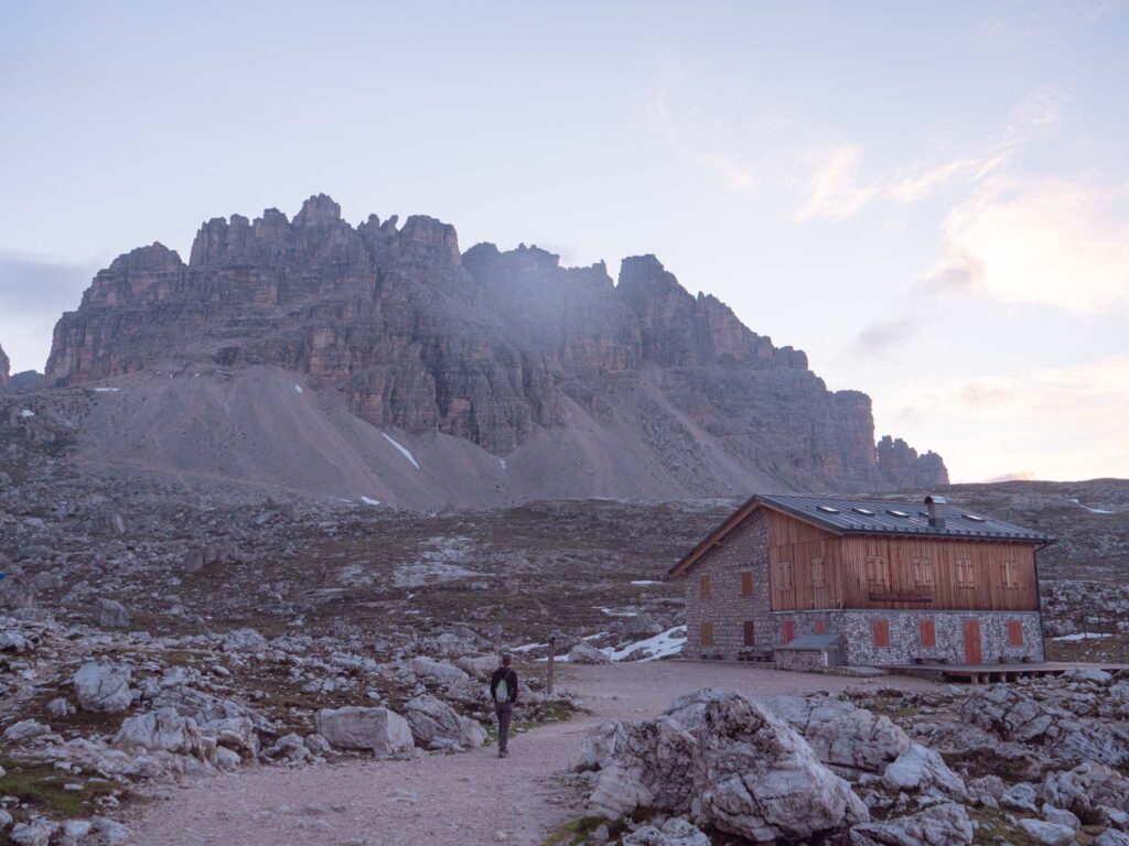 a person walking in front of a building in a rocky area