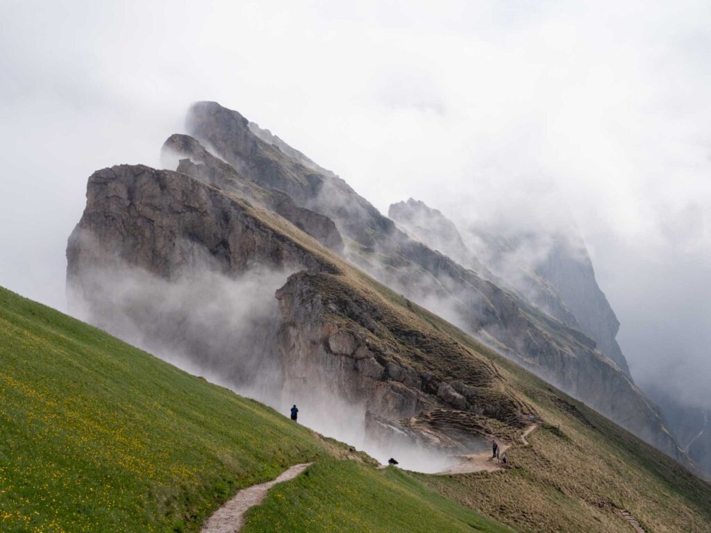 a person walking on a path on a grassy hill with fog