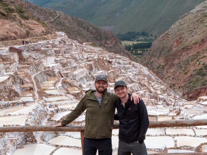 Two men standing near The Maras Salt Mines terraces in Peru
