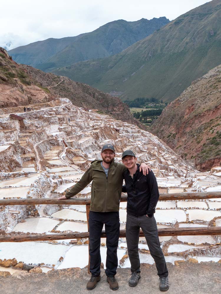 two men standing on a railing in front of a mountain