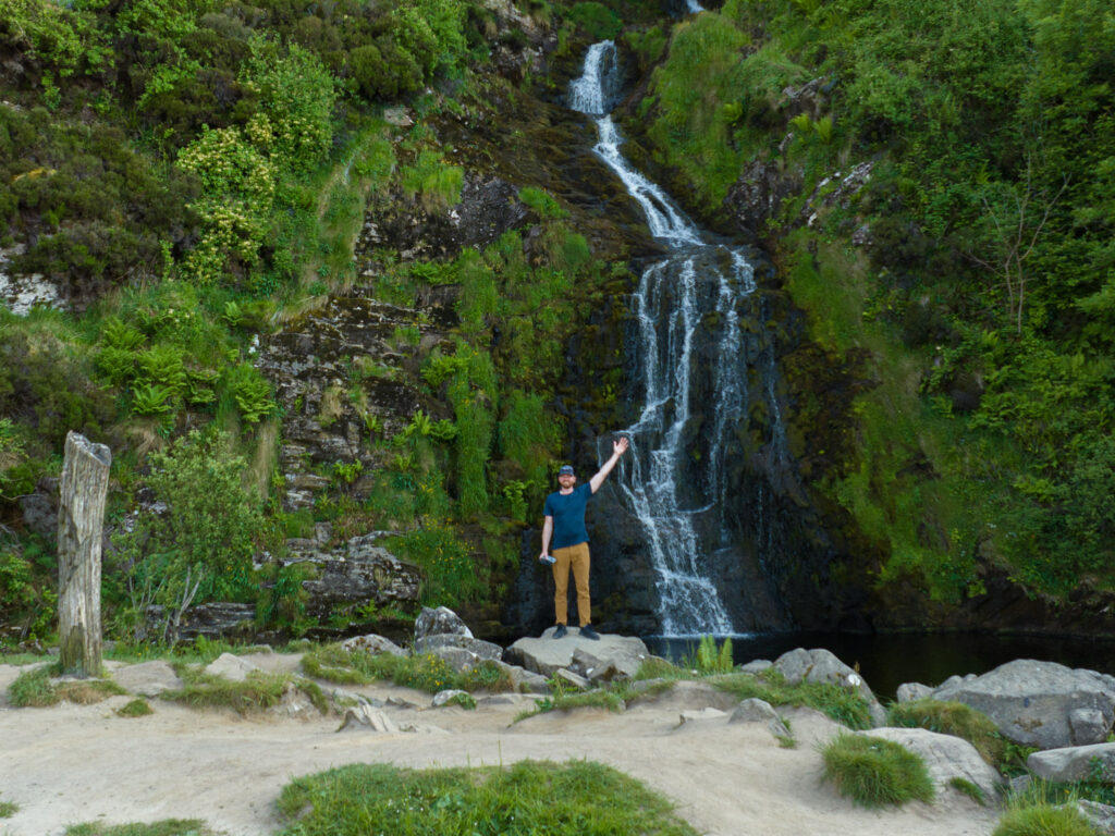 a man standing on a rock next to a waterfall