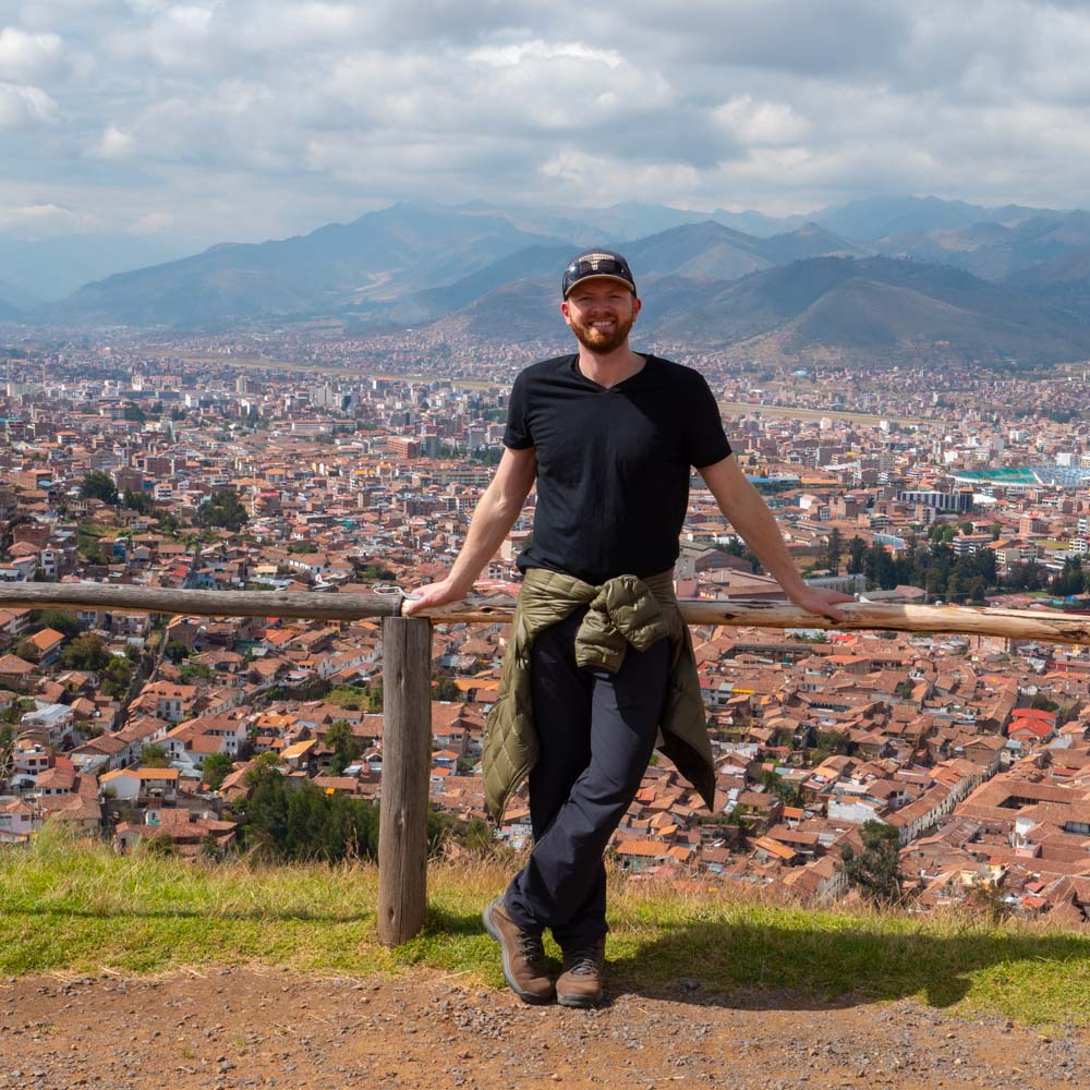 a man standing on a fence with a city in the background