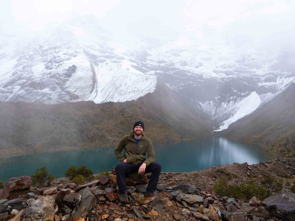 a man sitting on a rock with a lake in the background