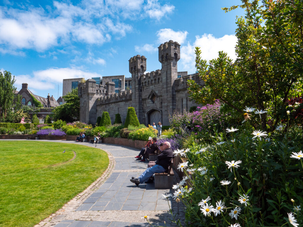 Large castle facade with people lounging near the green space