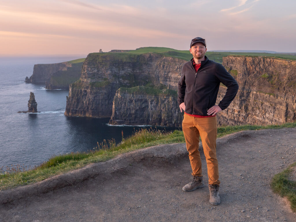 Man posing for photo in front of Cliffs of Moher