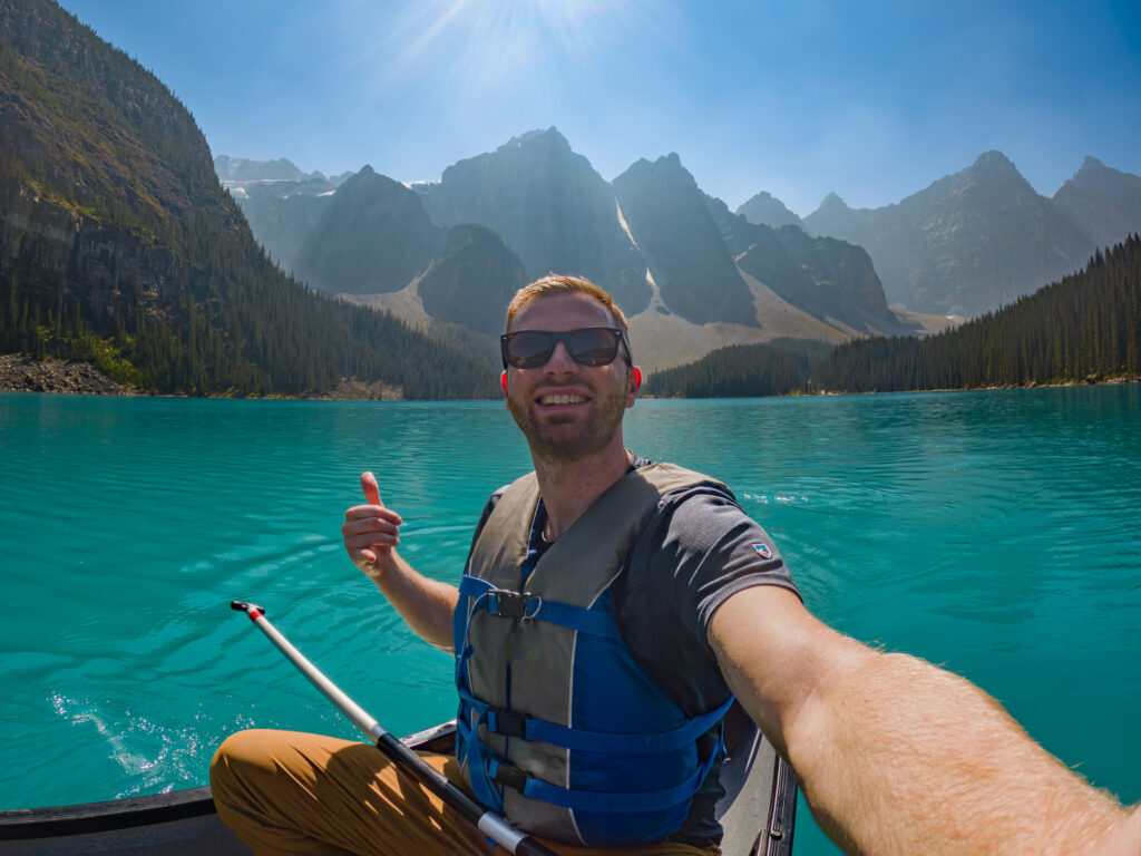 Man taking a selfie on a canoe in the middle of Moraine Lake in Banff National Park Canada