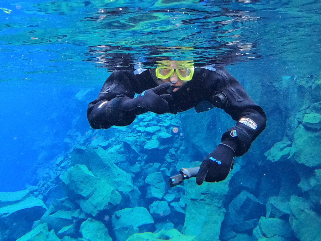 Man snorkeling in the blue waters of Silfra Iceland