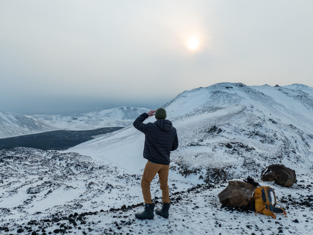 Man watching sunset during a volcano hike in snowy Iceland