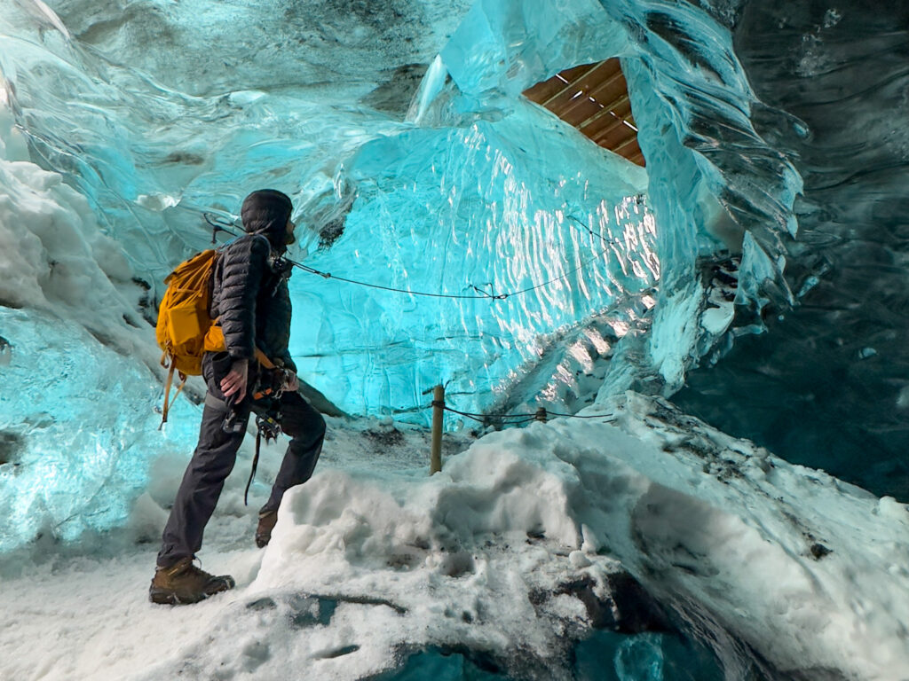 Hiker climbing a vivid blue ice cave staircase