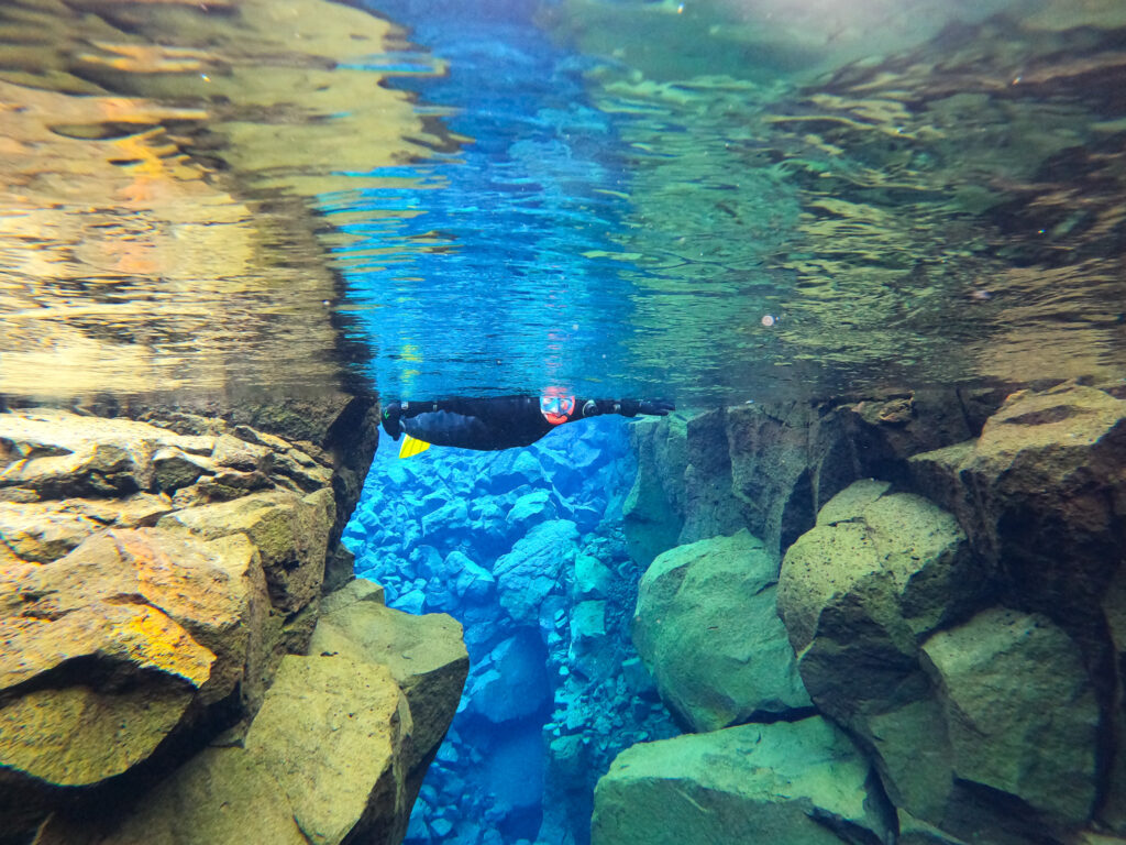 Person snorkeling between two large rock formations in Iceland