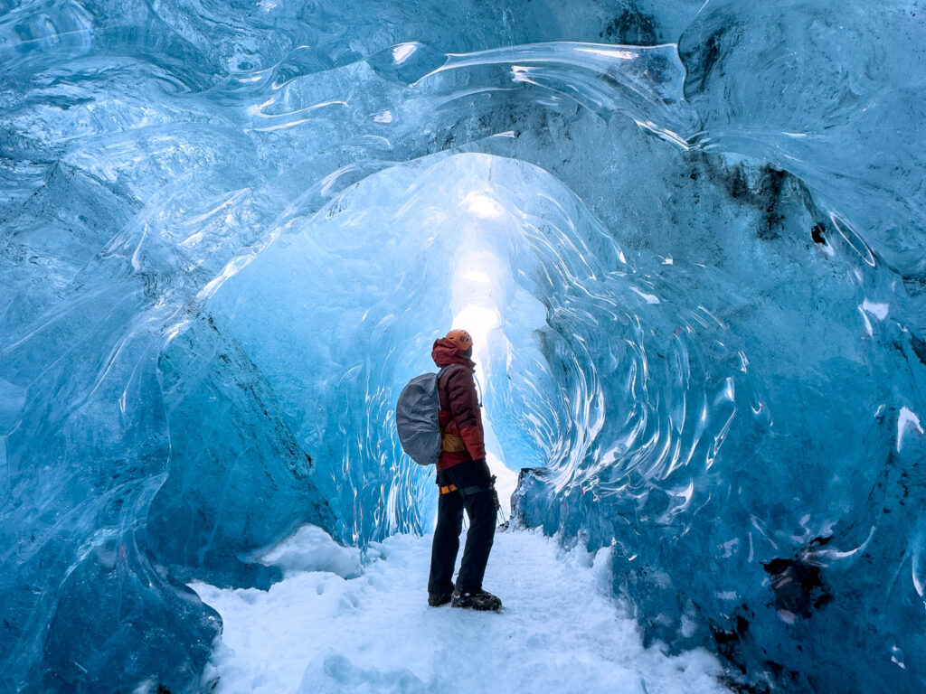 Hiker standing in an ice cave entrance