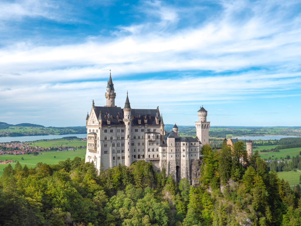 a castle with trees around it with Neuschwanstein Castle in the background